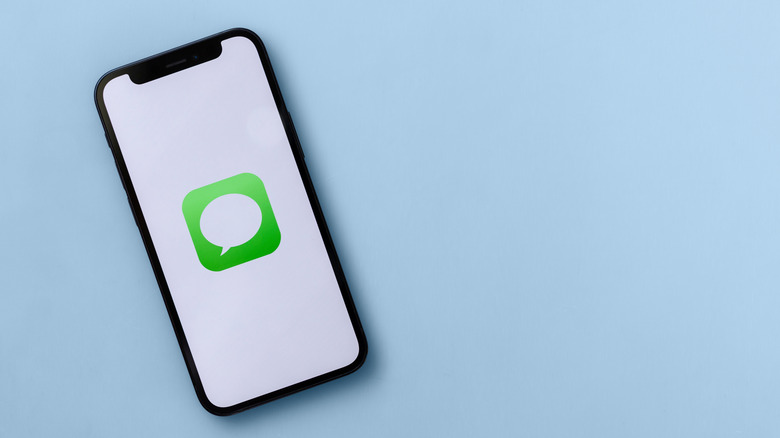 A photograph of an iPhone with the iMessage icon displayed on the screen.