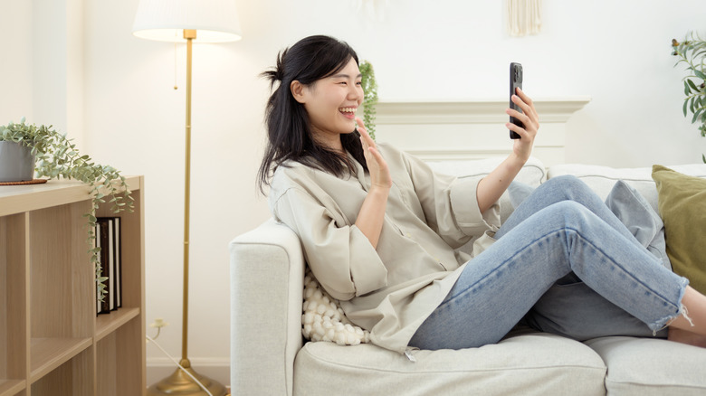 A woman sitting on a couch looking at a phone screen