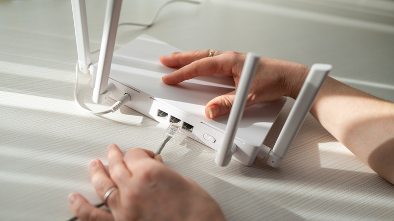 A person plugging in an Ethernet cable to a modem.