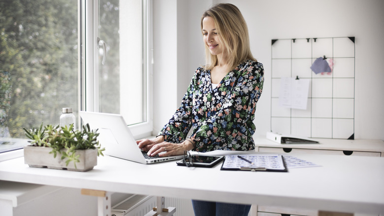 Woman working at a standing desk near a window