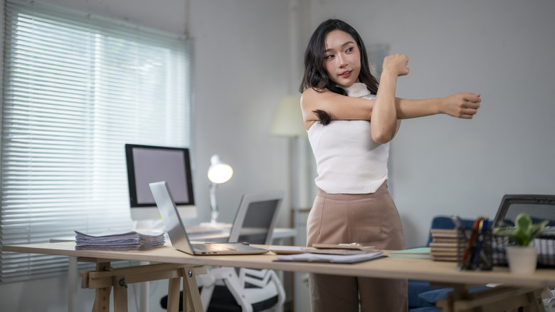 Woman stretching while using a standing desk