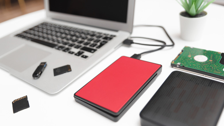 Various storage devices next to a laptop.