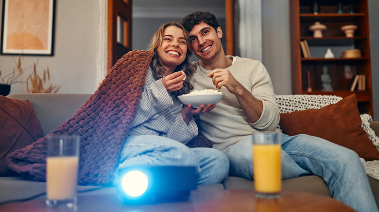 Couple sitting on sofa watching content via home projector