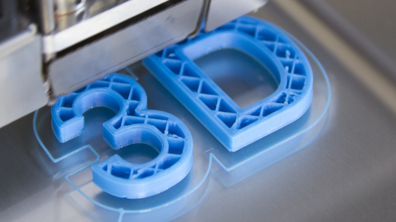A photo of blue characters 3 D being printed by a 3D printer.