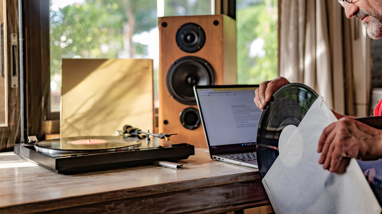 A man sleeving a record in front of an audio setup