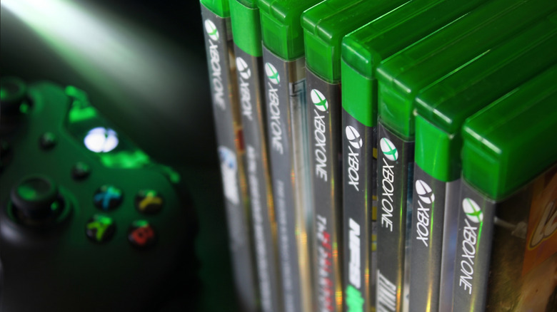 Xbox One games stacked near an Xbox One controller.