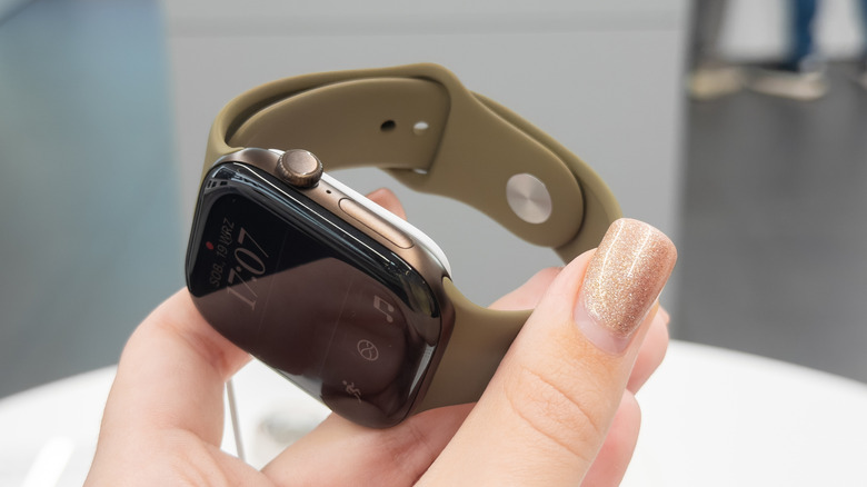 A gold Apple Watch Series 12 being held in a person's hand