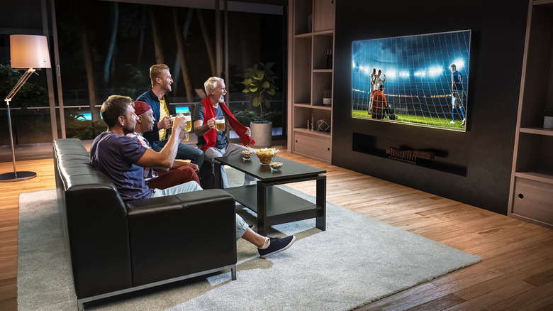 A group of friends watching a football game on a TV