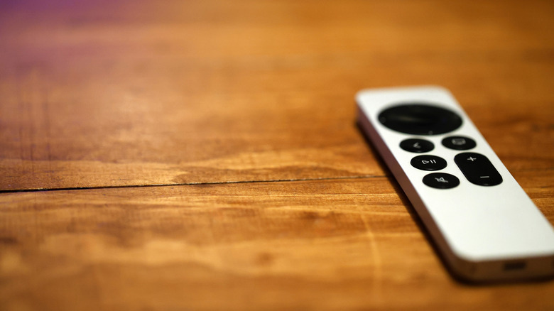 An Apple TV's included Siri remote placed on a flat wooden surface.