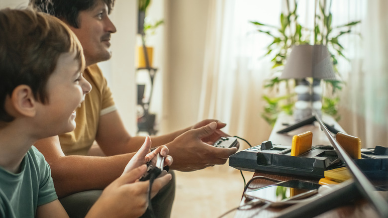 a family playing on a retro console while holding a controller with a console that has a loaded cartridge