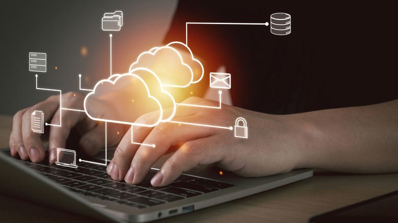 a person working on a laptop that shows a holographic symbols for cloud technology above the device