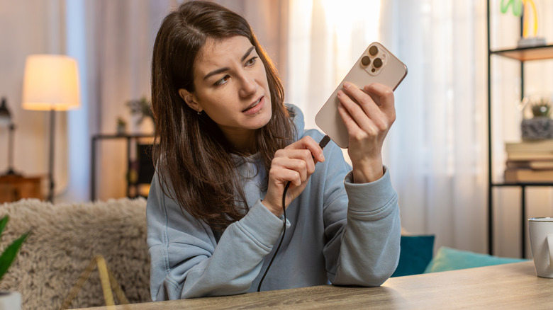 Woman plugging phone into charging cord to use power.