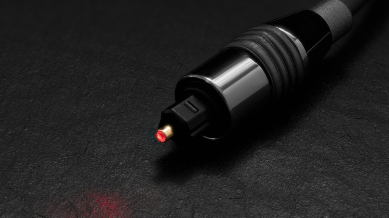 An optical audio cable sitting on a surface with the center glowing red