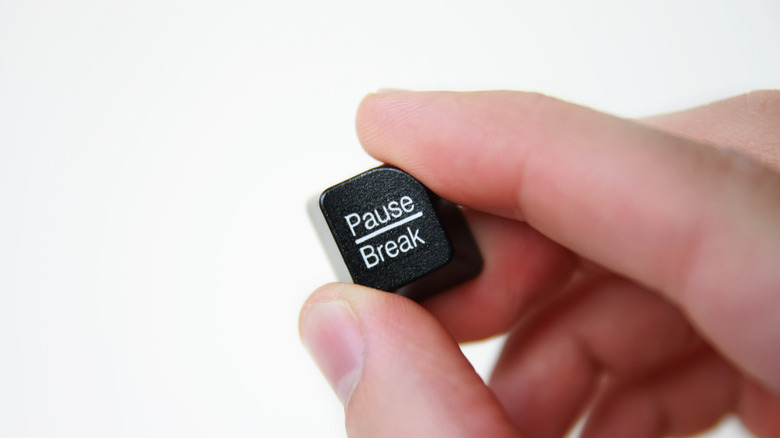 fingers holding a pause break key from a keyboard, customization concept