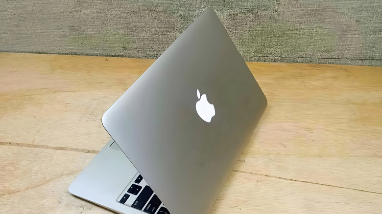 A MacBook half-opened on a flat wooden surface.