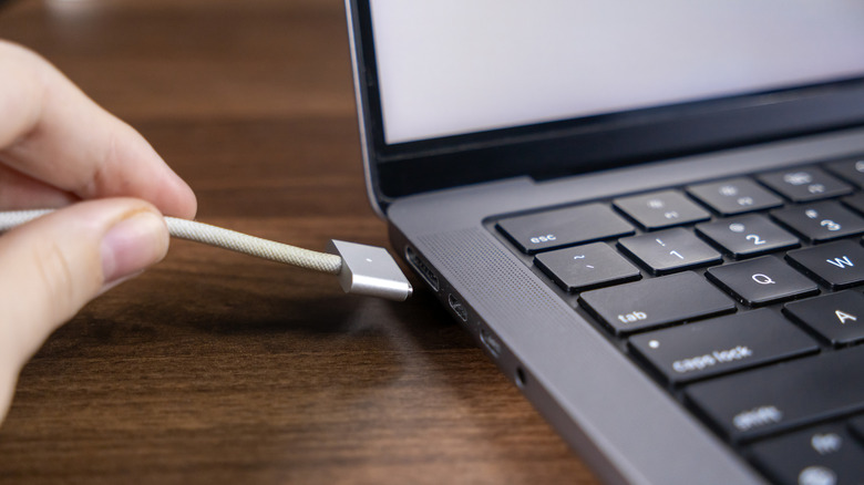 A person connecting a MagSafe 3 cable to a MacBook.