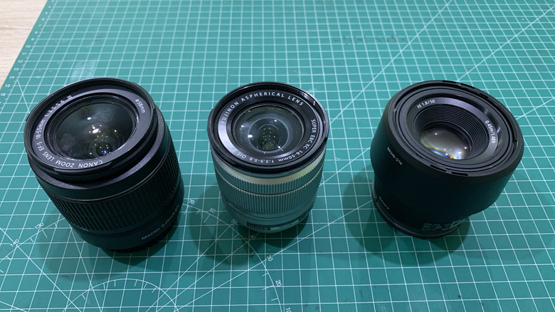Canon, Fujifilm, and Sony camera lenses lined up next to one another