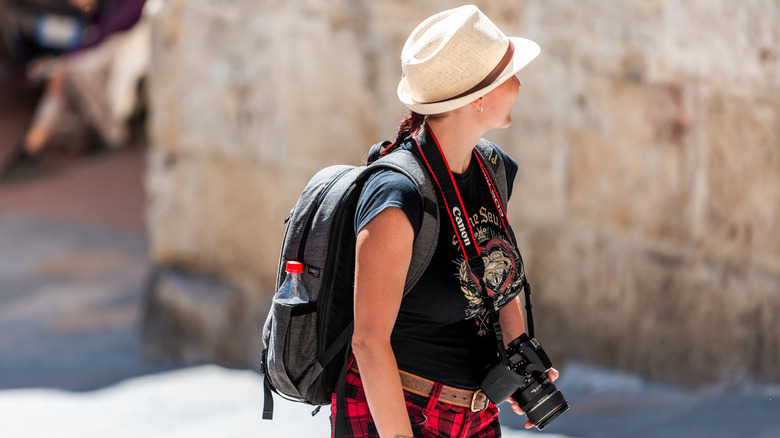 A tourist holds with a Canon camera with a Canon neck strap