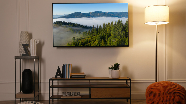 Modern TV mounted to a wall in a living room scene with the screen on.