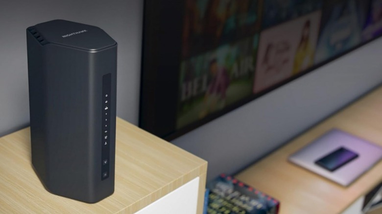 A NETGEAR Nighthawk Dual Band WiFi 7 Router (RS200) sitting on a wooden table with a tv in the background