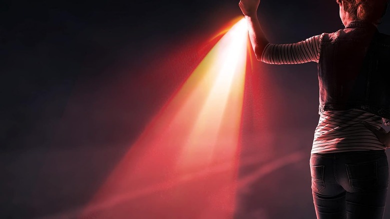 A woman shining a red flashlight on the ground