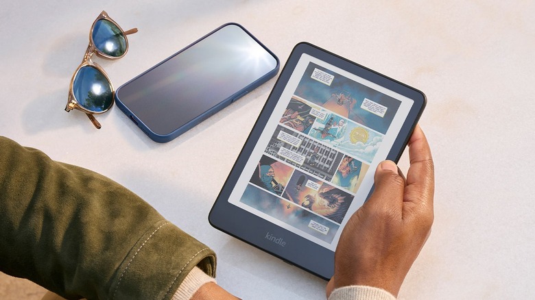 A hand holding a Kindle Colorsoft while reading comics