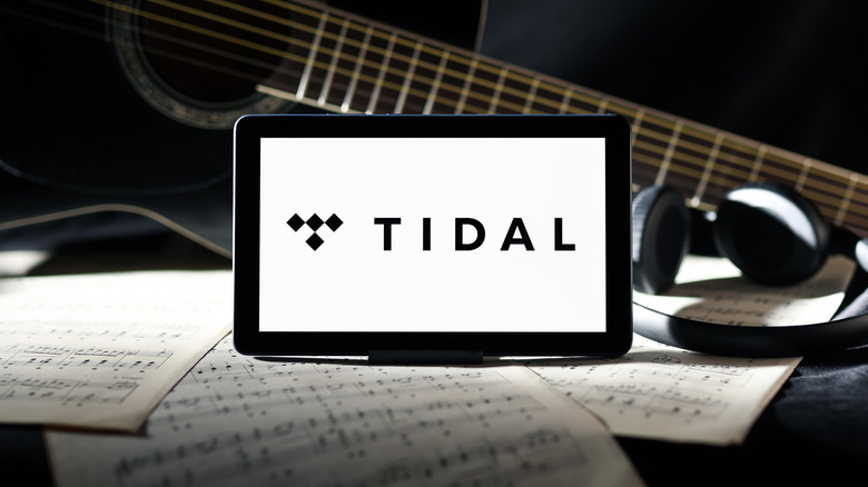 The Tidal logo displayed on a tablet screen among various musical paraphernalia