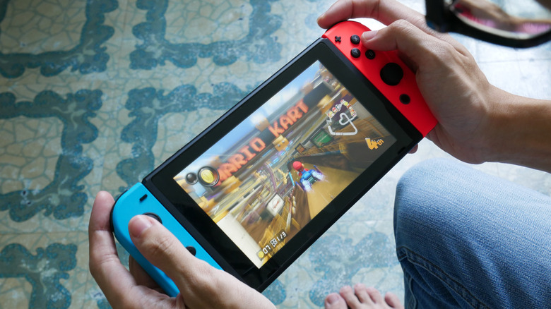 A close of a person's hands as they play Mario Kart on a Nintendo Switch