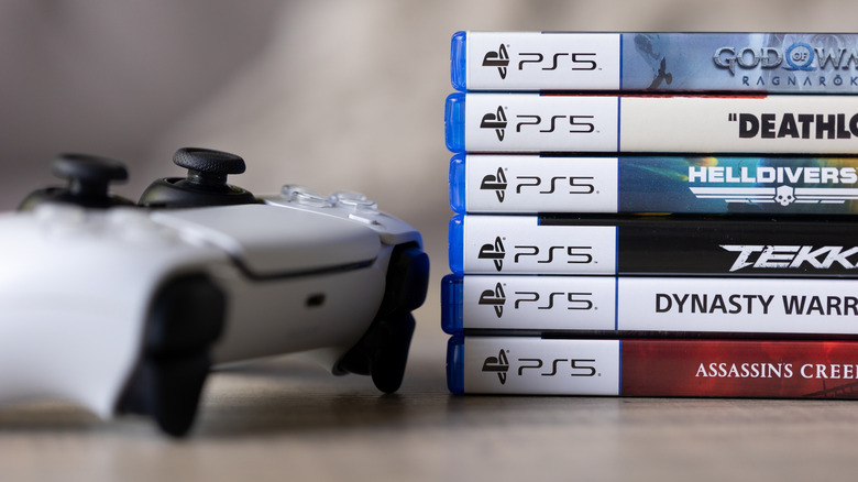 PlayStation 5 DualSense controller next to stack of game cases