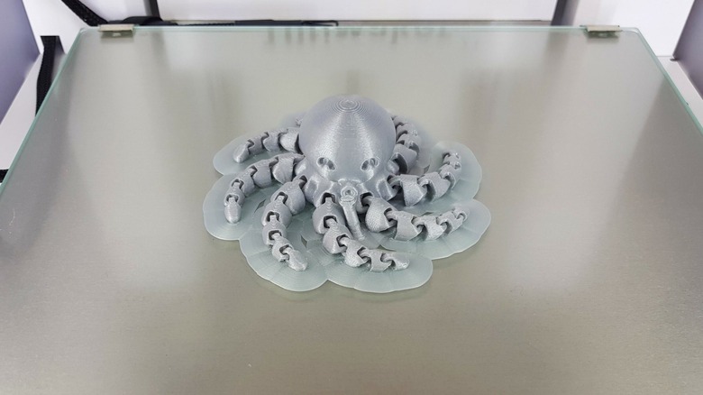 Gray 3D printed octopus with raft on printing bed