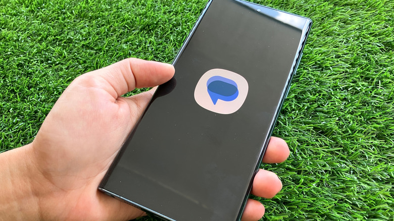 a hand holding a phone with the Samsung Messages icon on it