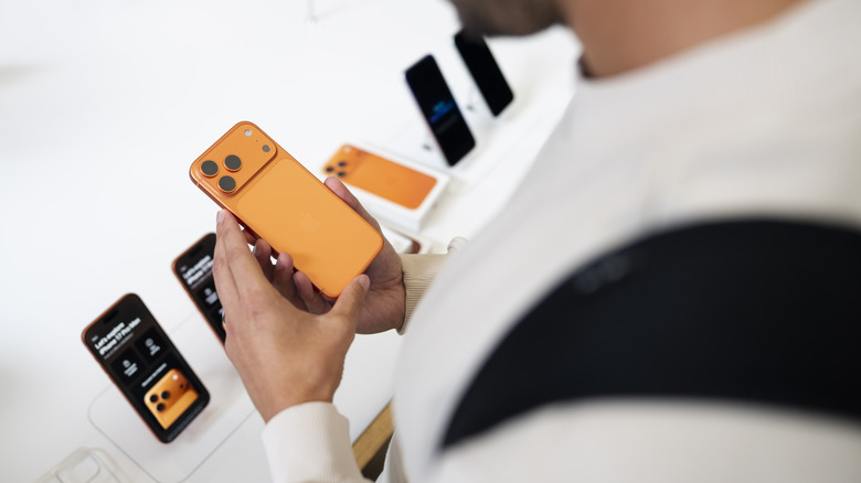 An iPhone 17 Pro model in hand in an Apple store.