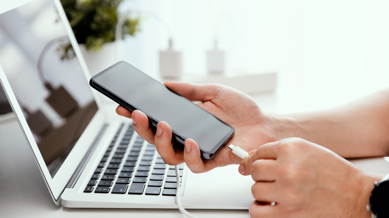A person charging an Android phone.