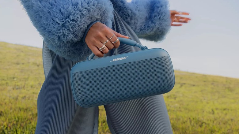 Hand holding Bose SoundLink Max Portable Speaker while walking
