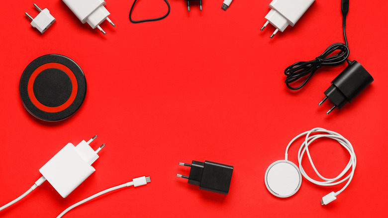Several power adapters and wireless chargers on red surface