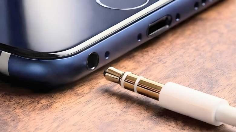 Close-up of a 3.5-millimeter audio plug with rings visible next to a smartphone port.