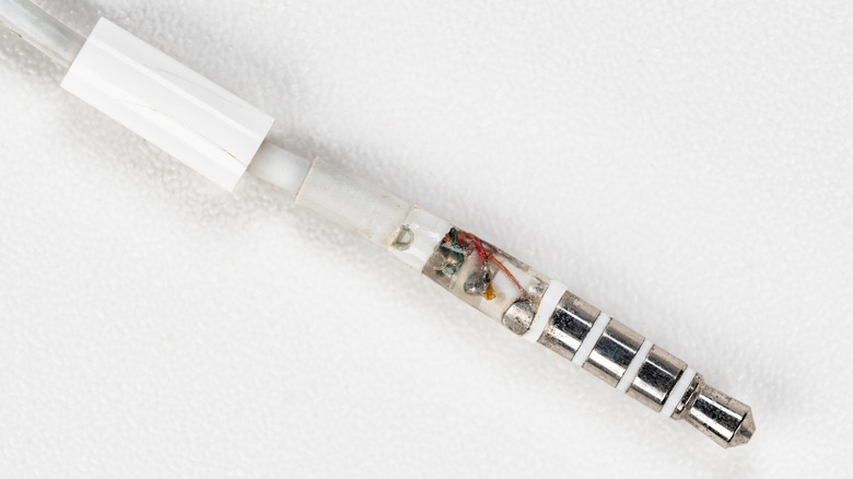 A broken 3.5-millimeter headphone jack with internal wires and rings visible.