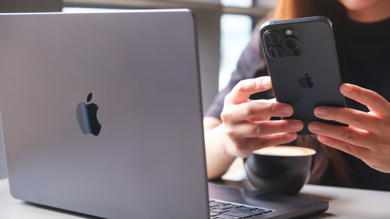 A person using an iPhone and a MacBook.