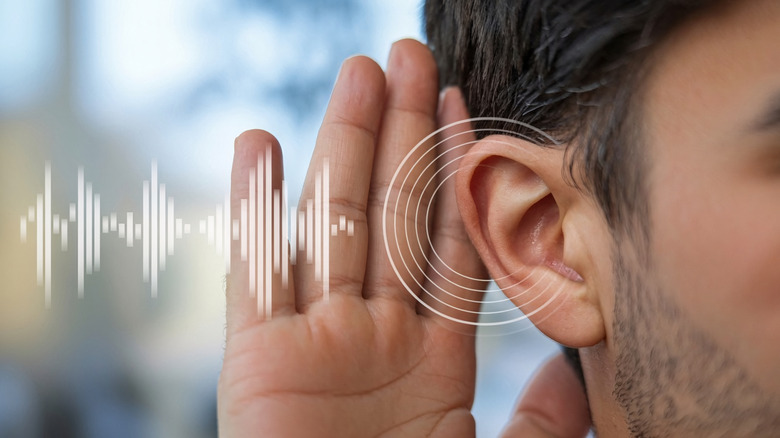 A man holding his hand to gus ear, with a sound waves graphic next to the ear