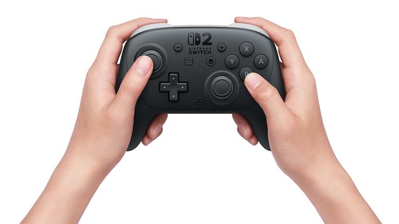 Person holding a Switch 2 Pro controller in front of a white background