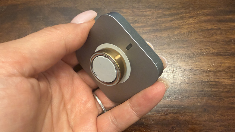 A hand holding an Oura Ring 4 on its charging dock, showing alignment with the notch.
