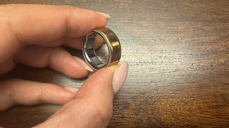 Fingers holding an Oura Ring 4, showing the notch on the underside.