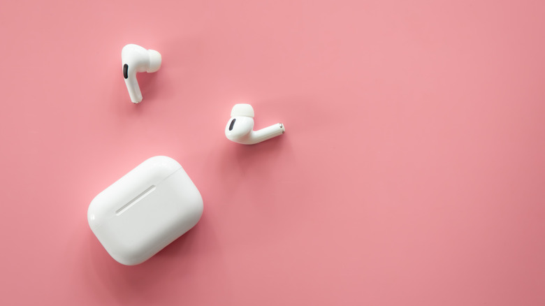 A pair of Apple AirPod set against a pink backdrop.