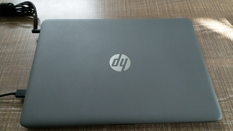 hp laptop plugged into charging on a wooden desk