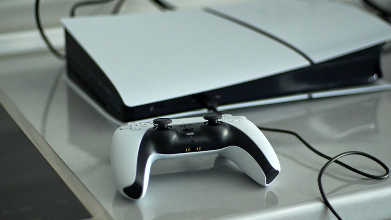 A PlayStation 5 and DualSense controller placed on top of a glossy gray surface.