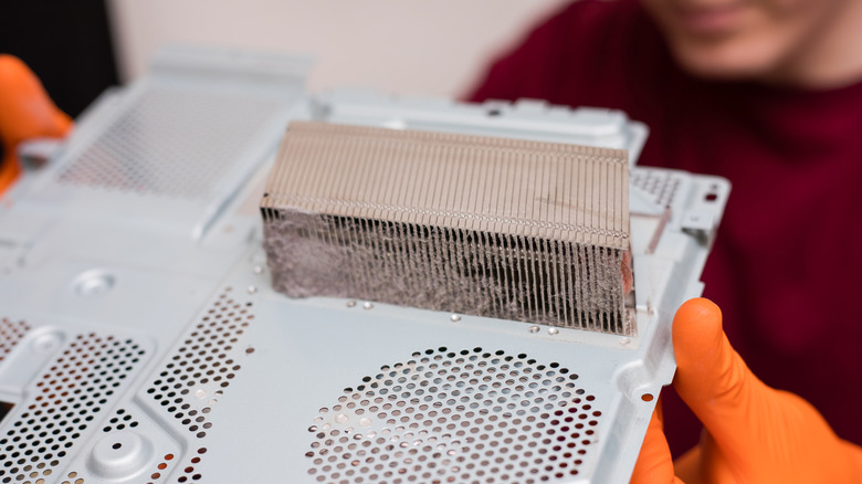 Hands holding dusty PlayStation 4 part