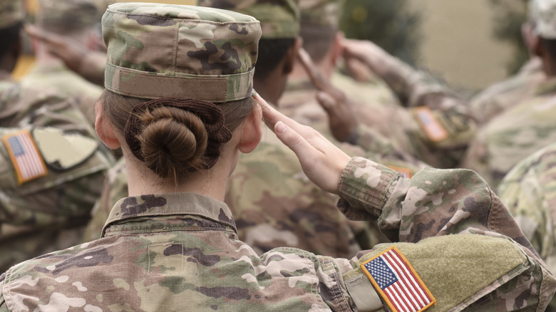 the back of a female soldier in a group of US military soldiers saluting