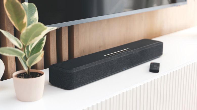 A soundbar placed on top of an entertainment center, below a wall-mounted TV.