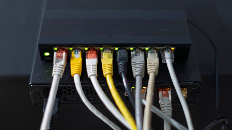 Router with several ethernet cables plugged in showing multiple green lights and an amber light