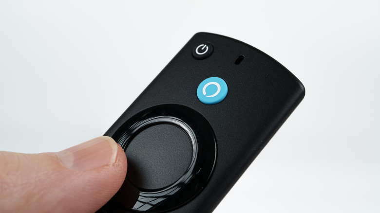 A close-up of a person's finger on an Alexa Voice Remote (provided with a Fire TV device purchase).